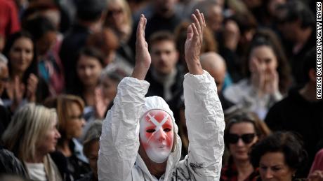 V Ženevě 9. října 2021 tleskal demonstrant s maskou zobrazující injekce a kompletním ochranným oblekem.