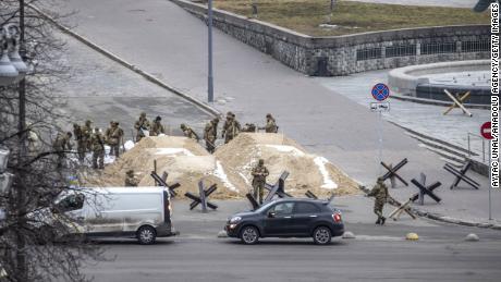Vojáci sledují hromady písku, které blokovaly silnici v ukrajinském hlavním městě Kyjevě.