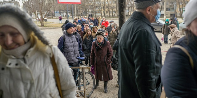 Lidé se 14. března 2022, třetí týden ruské invaze na Ukrajinu, postaví do fronty na distribuci potravin před supermarketem v Mykolajivu. 