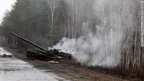 Z ruského tanku zničeného ukrajinskými silami na kraji silnice v Luganské oblasti 26. února 2022 stoupá kouř.