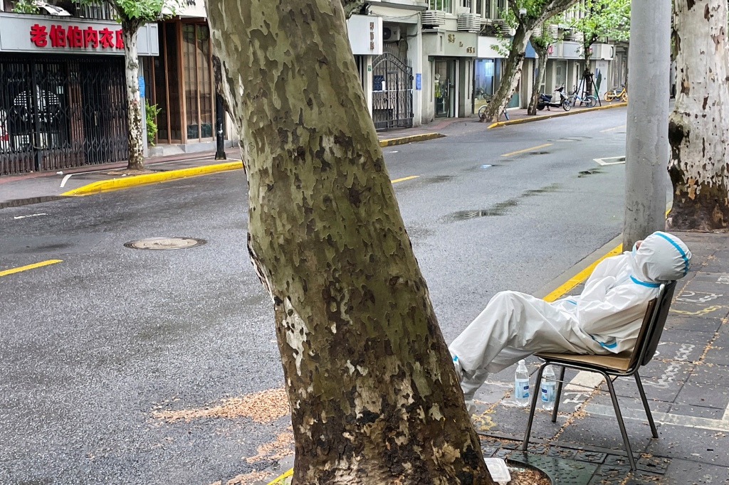 Unavený lékař sedí na prázdné ulici v čínské Šanghaji.