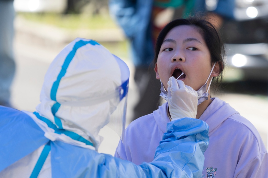 Dívce se 22. dubna 2022 v čínské Šanghaji provede výtěr z úst kvůli testu na COVID-19.