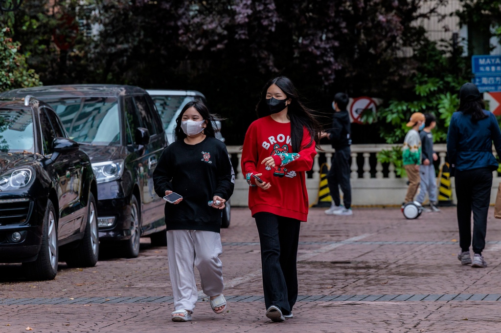 Lidé procházejí obytnou komunitou pod uzamčením v Šanghaji v Číně, 23. dubna 2022.