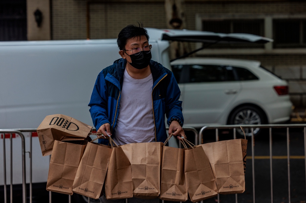 Doručovatel přináší jídlo do uzavřené rezidenční komunity v Šanghaji, Čína, 23. dubna 2022.