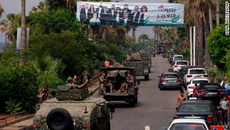 Vozidla libanonské armády míjejí billboard zobrazující kandidáty do parlamentních voleb v neděli v libanonském Bejrútu 14. května.