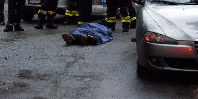 Hasiči stojí vedle mrtvého těla na místě útoku v Cetinje v Černé Hoře v pátek 12. srpna 2022. 