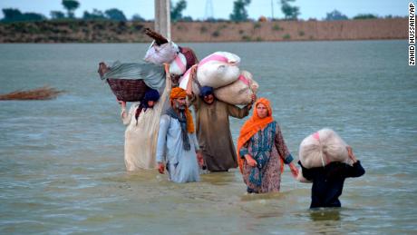 Vysídlená rodina se 24. srpna brodí v zaplavené oblasti v Džafarabádu, okrese pákistánské jihozápadní provincie Balúčistán.