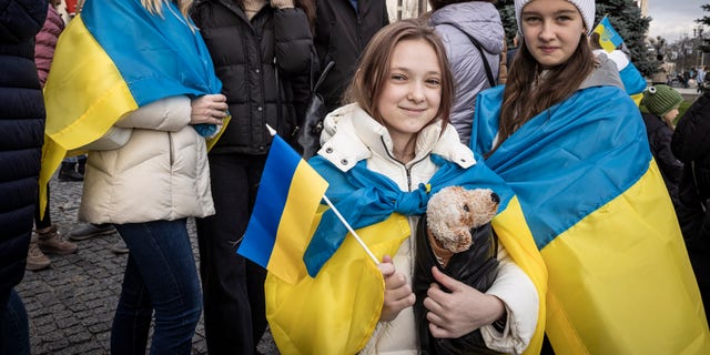 Lidé pijí sekt, mávají vlajkami a zpívají písně při oslavách osvobození části Chersonu na náměstí Nezávislosti 12. listopadu 2022 v Kyjevě na Ukrajině. 